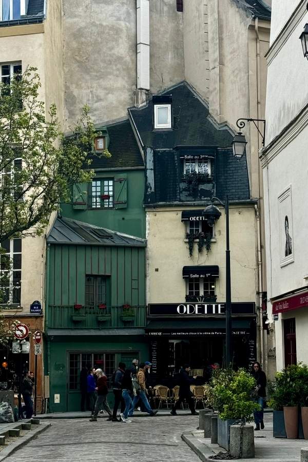 Scorcio incantevole di Parigi nel Quartiere Latino, vicino a Notre Dame, con una tradizionale boulangerie e palazzi dipinti in verde e crema, caratterizzati dai tipici tetti parigini. Un'atmosfera affascinante che cattura l'essenza della capitale francese.